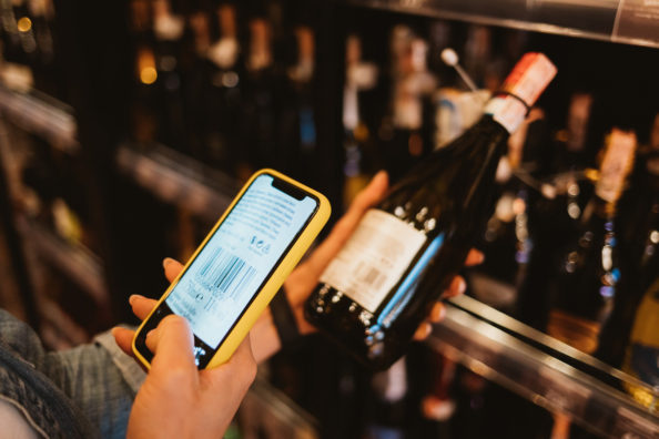 Woman customer scanning barcode from wine bottle label using sma